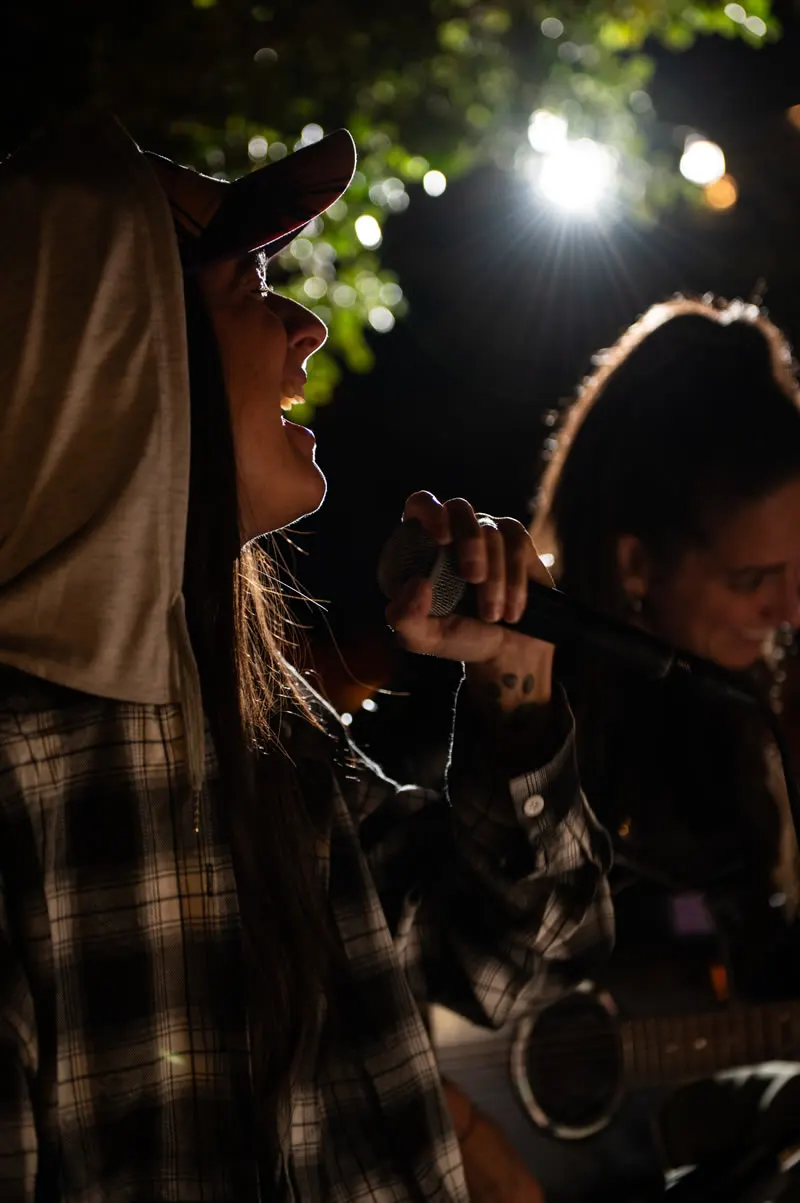 Cantante al microfono durante una serata live sotto gli alberi di Jaga
